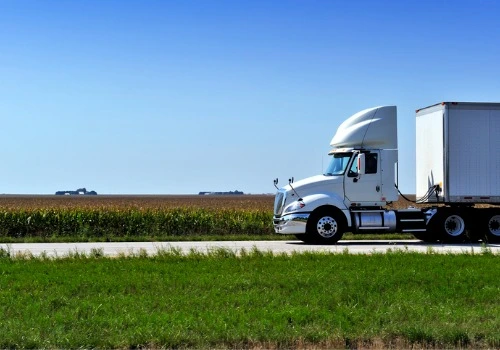 A white truck next to a farm field, performing Freight Shipping in Ohio